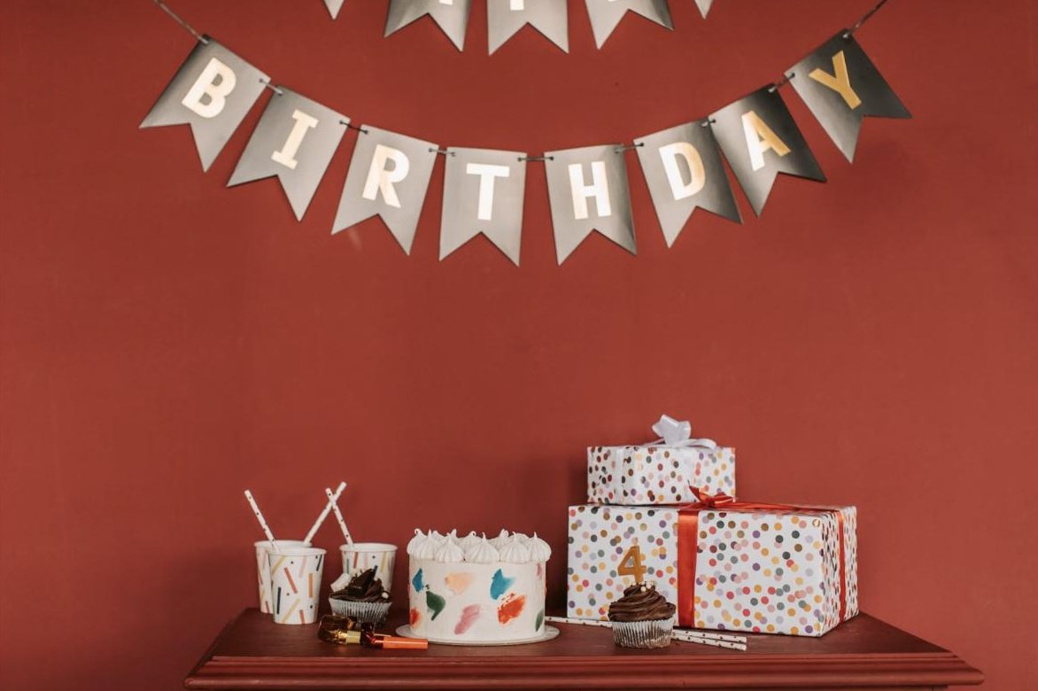Happy Birthday bunting hanging over a table with a cake and gifts