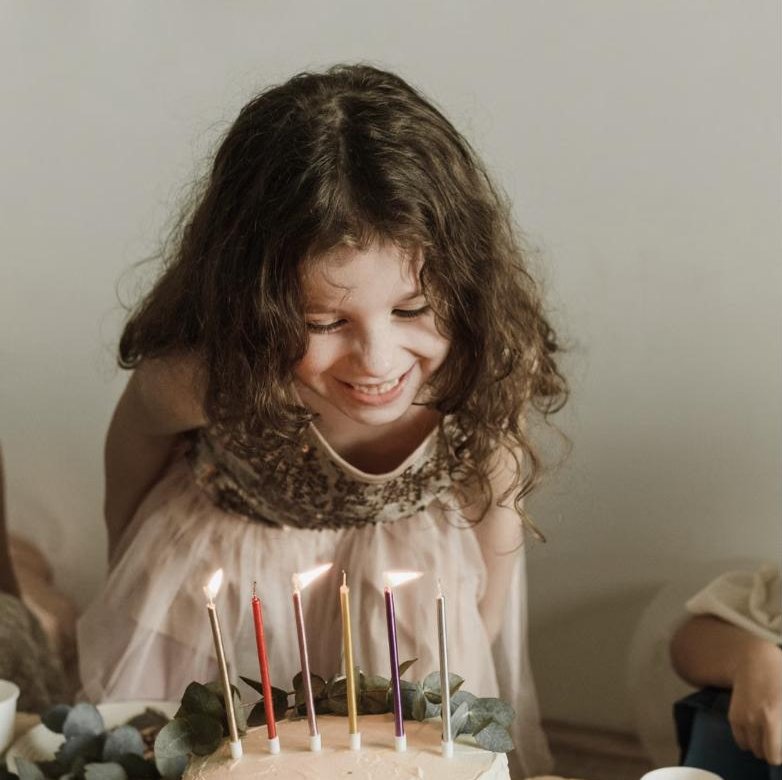 A girl smiling over her birthday cake with lit candles